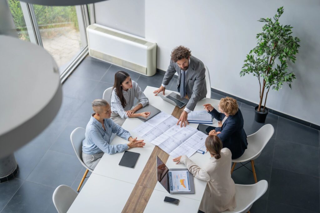 Business team analyzing blueprints during meeting in modern office
